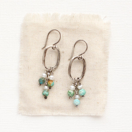 The seaside hoop earrings styled on tan linen