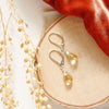 The silver citrine drop earrings styled on wood with orange velvet and dried grass