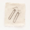 The silver open bar earrings styled on tan linen