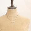 A mannequin wearing the silver open bar necklace