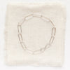 The silver paperclip bracelet styled on tan linen