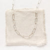 The bright silver paperclip necklace styled on tan linen