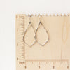 The silver pointed hoop earrings on a wooden ruler for size reference