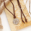 The silver wanderer medallion adjustable leather necklace styled on a tan rock with brown velvet and dried grass