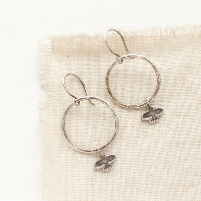 The soar hoop earrings styled on tan linen