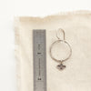 A soar hoop earring next to a ruler for size reference