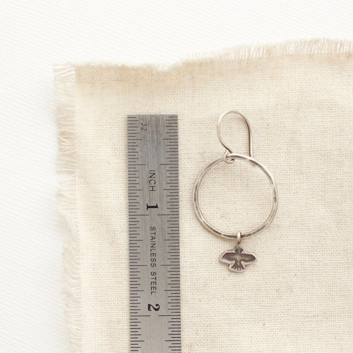 A soar hoop earring next to a ruler for size reference