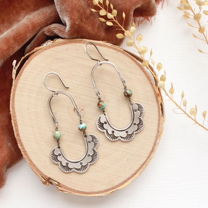 The speckled turquoise columbine hoop earrings styled on wood with orange velvet and dried grass