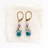 The stacked capri earrings styled on tan linen