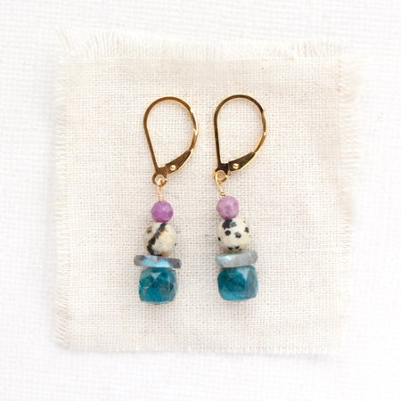 The stacked capri earrings styled on tan linen