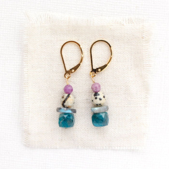 The stacked capri earrings styled on tan linen