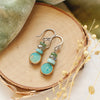 The stacked marin earrings styled on wood with green velvet and dried grass