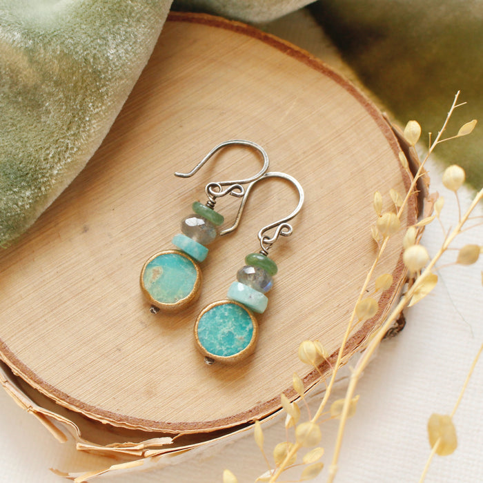 The stacked marin earrings styled on wood with green velvet and dried grass