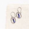 The stacked lapis mini hoop earrings styled on tan linen