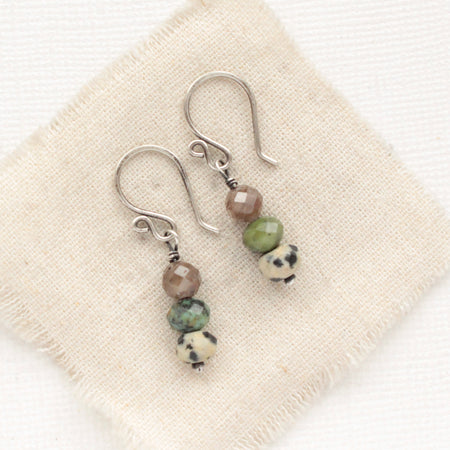 The stacked lona earrings styled on tan linen