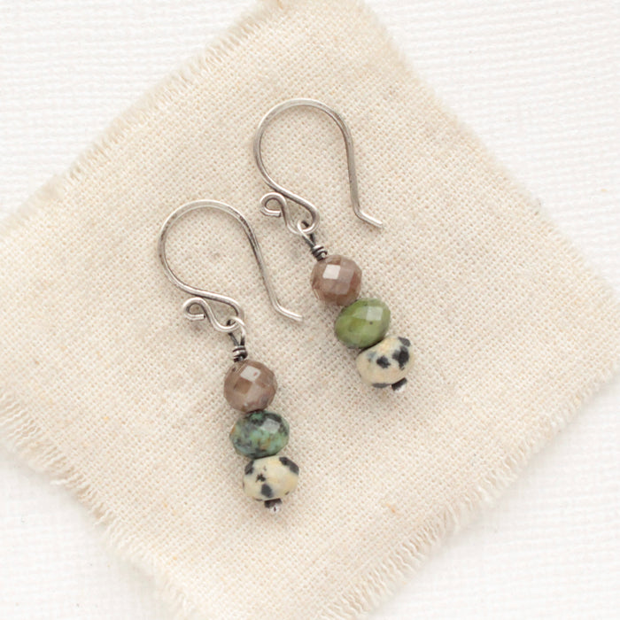 The stacked lona earrings styled on tan linen