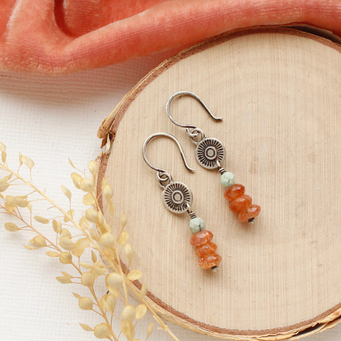The stacked mesa talara sun earrings styled on wood with orange velvet and dried grass