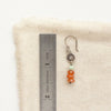 A stacked mesa talara sun earring next to a ruler for size reference