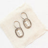 The stacked pearl mini hoop earrings styled on tan linen
