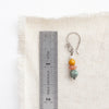 A stacked sunset earring next to a ruler for size reference