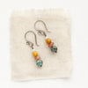 The stacked sunset earrings styled on tan linen