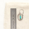 A stacked turquoise mini hoop earring next to a ruler for size reference