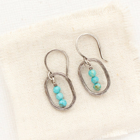 The stacked turquoise mini hoop earrings styled on tan linen