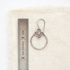 A talara hoop earring next to a ruler for size reference