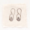 The wanderer hoop earrings styled on tan linen