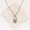 The wanderer hoop necklace styled on tan linen