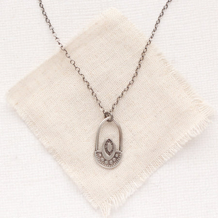 The wanderer hoop necklace styled on tan linen