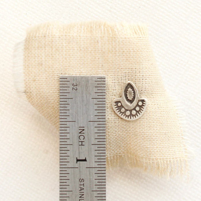 A wanderer post earring next to a ruler for size reference