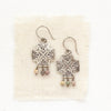 The sun cross rainbow agate earrings styled on tan linen