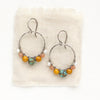 The sunset hoop earrings styled on tan linen