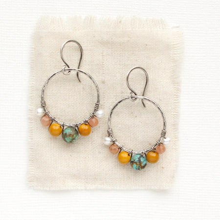 The sunset hoop earrings styled on tan linen