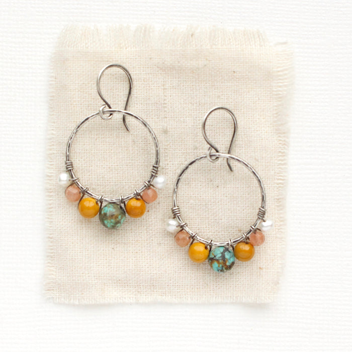 The sunset hoop earrings styled on tan linen