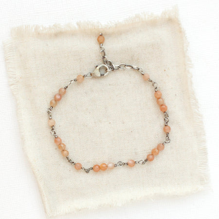 The wrapped sunstone bracelet styled on tan linen
