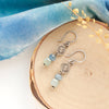 The talara sun aquamarine earrings styled on wood with blue velvet and dried grass