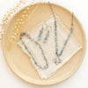 The talara sun kyanite bracelet styled with the matching earrings and matching necklace on a tan plate with dried grass