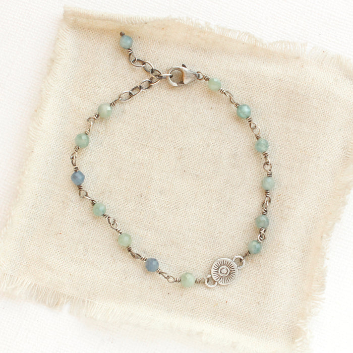 The silver wrapped kyanite talara sun bracelet styled on tan linen