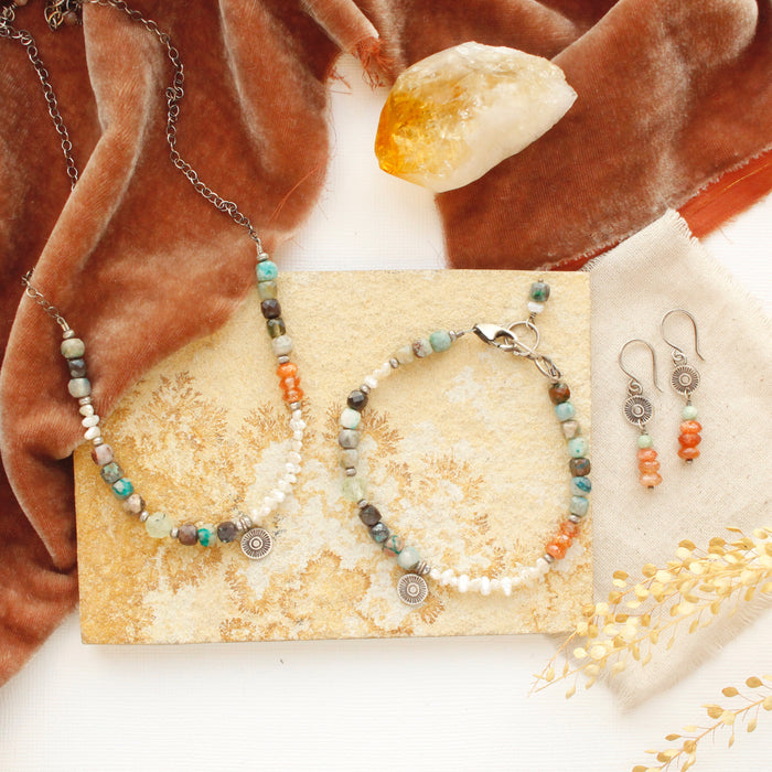 The talara sun mesa pieces styled on a tan rock with orange velvet and a crystal
