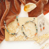 The talara sun mesa necklace, earrings, and bracelet styled on a tan rock with orange velvet and a crystal