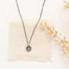 The talara sun necklace styled on tan linen with dried grass
