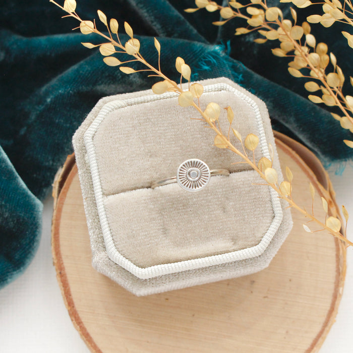 The talara sun ring styled on a velvet box with wood, blue velvet, and dried grass