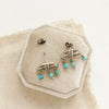 The turquoise pakal arch post earrings styled on a velvet box with linen
