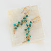 The turquoise wrapped gold vine earrings styled on tan linen