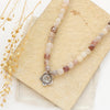 The layered cactus flower violet jade necklace styled on a tan rock with linen and dried grass