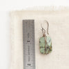 A wrapped african jasper earring next to a ruler for size reference