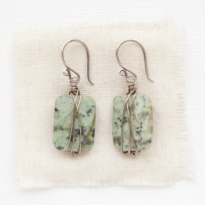 The wrapped african jasper earrings styled on tan linen