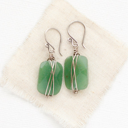 The wrapped green aventurine earrings styled on tan linen
